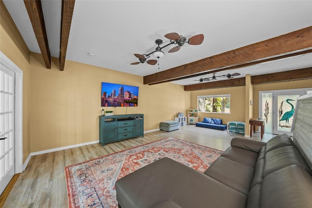 living area with beamed ceiling, a ceiling fan, light wood-type flooring, and baseboards