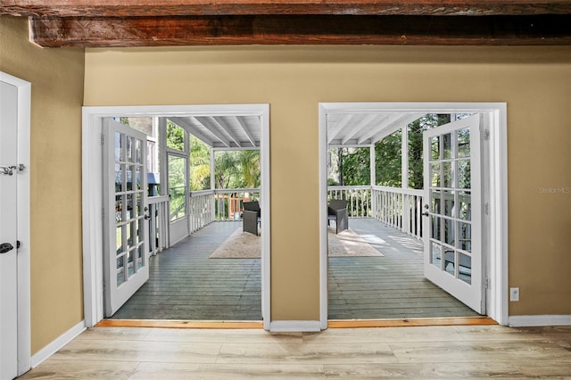 doorway with hardwood / wood-style floors, beamed ceiling, and baseboards