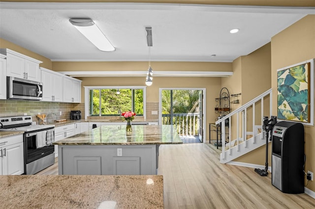 kitchen featuring light wood-type flooring, decorative backsplash, appliances with stainless steel finishes, and white cabinets