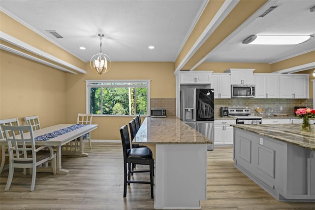 kitchen featuring visible vents, a kitchen bar, light wood-style floors, appliances with stainless steel finishes, and white cabinets