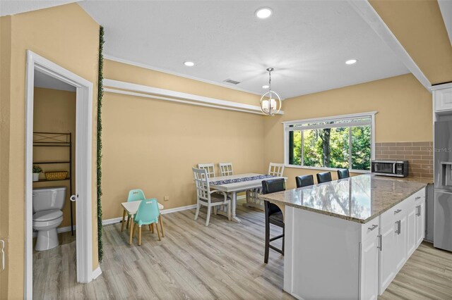 kitchen featuring light wood-type flooring, tasteful backsplash, a peninsula, and white cabinets