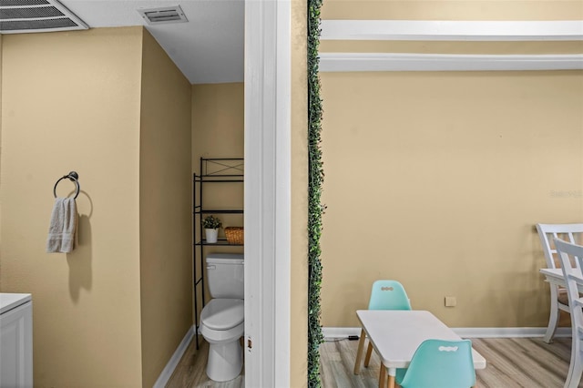 bathroom with visible vents, baseboards, toilet, and wood finished floors