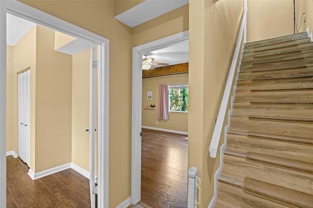 staircase with a ceiling fan, wood finished floors, and baseboards