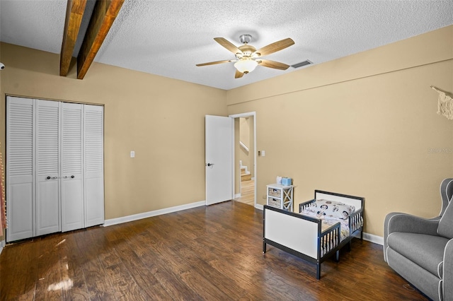 sitting room with beamed ceiling, a textured ceiling, wood finished floors, baseboards, and ceiling fan