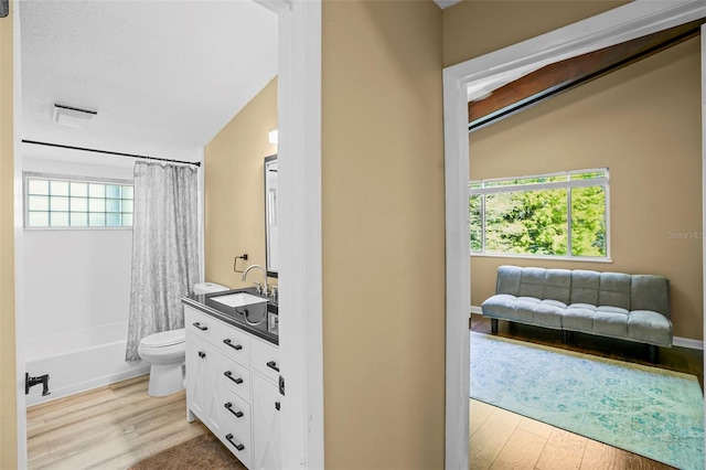 bathroom featuring vanity, shower / bathtub combination with curtain, wood finished floors, lofted ceiling, and toilet