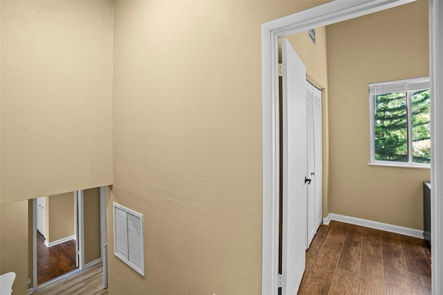 hall with visible vents, baseboards, and wood finished floors