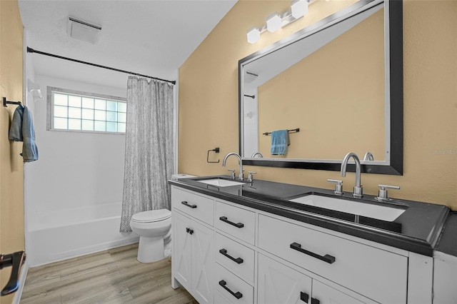 full bathroom featuring double vanity, toilet, wood finished floors, and a sink