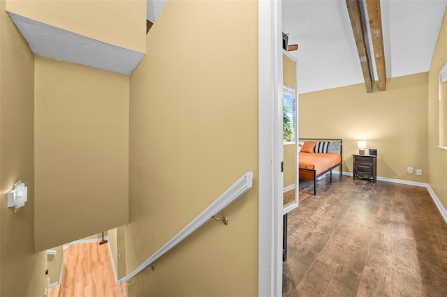 stairway featuring beamed ceiling, baseboards, and wood finished floors