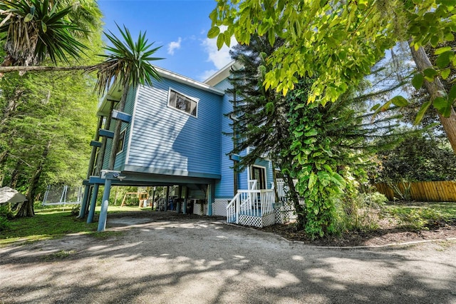 view of property exterior with a carport, driveway, and fence