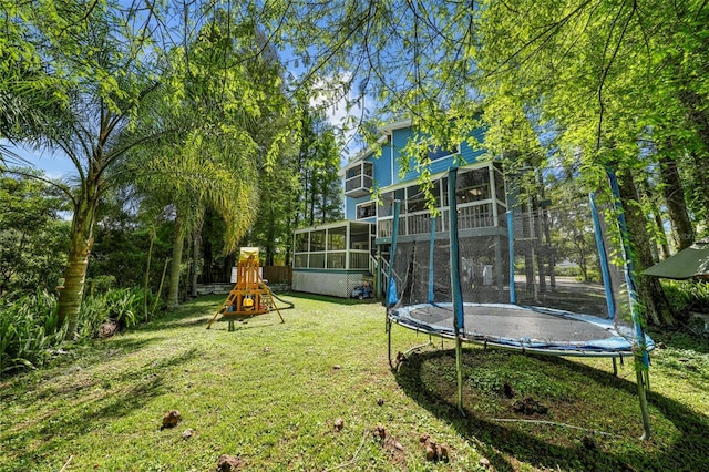 view of yard with a playground, a trampoline, and a sunroom