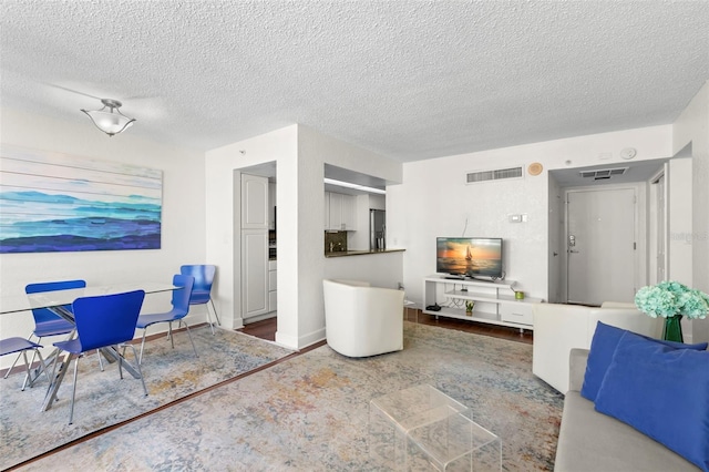 living area with visible vents, a textured ceiling, and baseboards