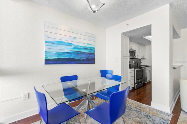 dining space featuring dark wood-style floors, a textured ceiling, and baseboards