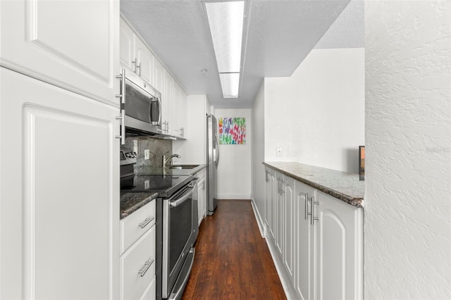 kitchen with tasteful backsplash, dark wood finished floors, appliances with stainless steel finishes, white cabinetry, and a sink