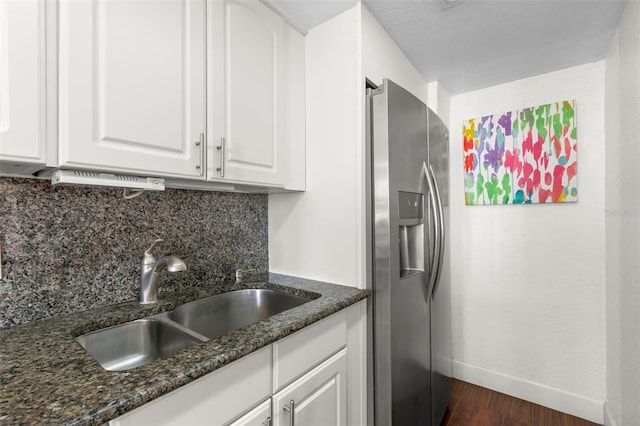 kitchen featuring a sink, tasteful backsplash, white cabinets, stainless steel fridge with ice dispenser, and baseboards