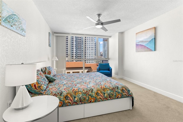 carpeted bedroom with a city view, a textured ceiling, baseboards, ceiling fan, and a textured wall