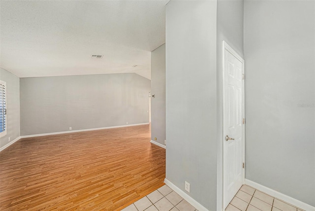 bonus room featuring visible vents, baseboards, light wood-type flooring, vaulted ceiling, and a textured ceiling