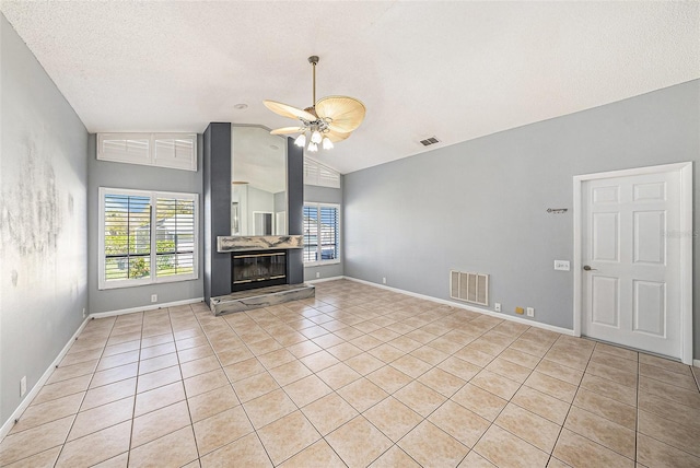 unfurnished living room with a glass covered fireplace, vaulted ceiling, a ceiling fan, and visible vents