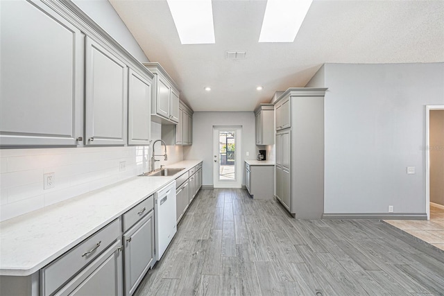 kitchen with a sink, dishwasher, a skylight, and gray cabinets