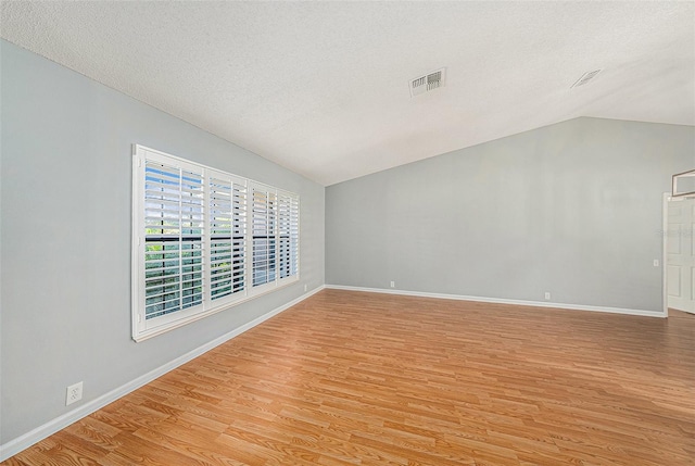 unfurnished room with vaulted ceiling, baseboards, visible vents, and light wood-type flooring