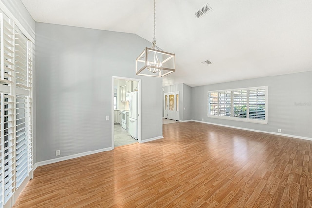 unfurnished living room featuring an inviting chandelier, baseboards, visible vents, and light wood-type flooring