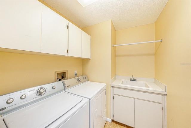 laundry area with washing machine and clothes dryer, cabinet space, a textured ceiling, and a sink