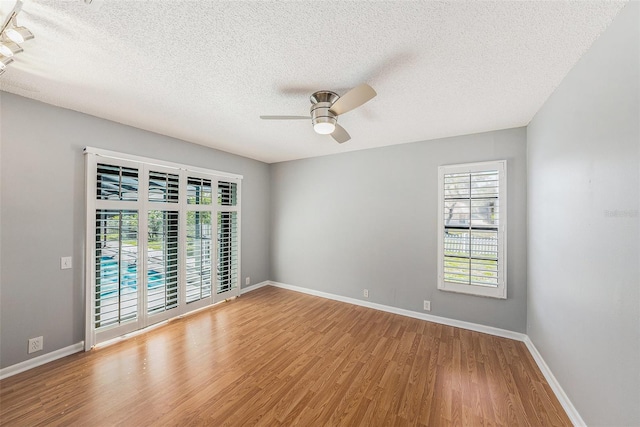 spare room featuring a textured ceiling, wood finished floors, baseboards, and ceiling fan