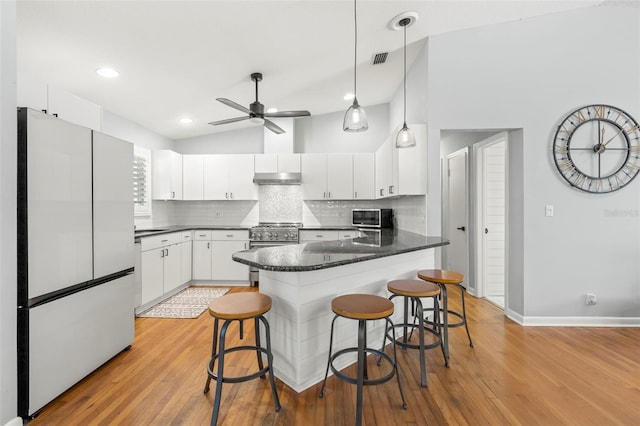 kitchen with visible vents, a peninsula, stainless steel appliances, under cabinet range hood, and dark countertops