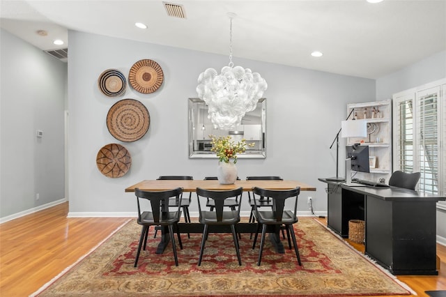 dining space with visible vents, a notable chandelier, and wood finished floors