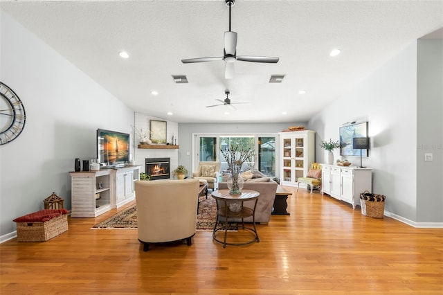 living room with recessed lighting, a fireplace, visible vents, and light wood finished floors