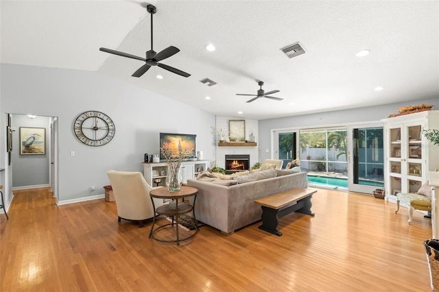 living area with vaulted ceiling, wood finished floors, visible vents, and baseboards