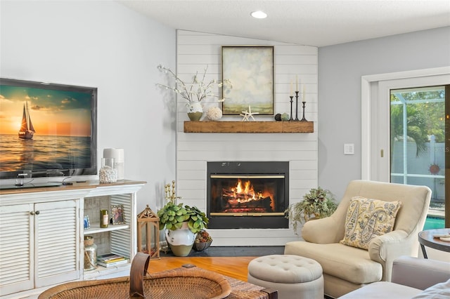 living area featuring recessed lighting, a large fireplace, lofted ceiling, and wood finished floors