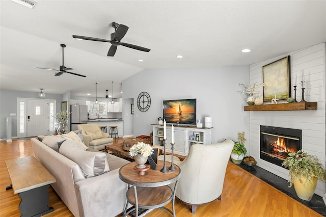 living area featuring a ceiling fan, lofted ceiling, light wood-style flooring, recessed lighting, and a fireplace