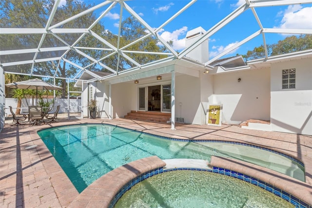 view of pool with glass enclosure, a patio, and a pool with connected hot tub