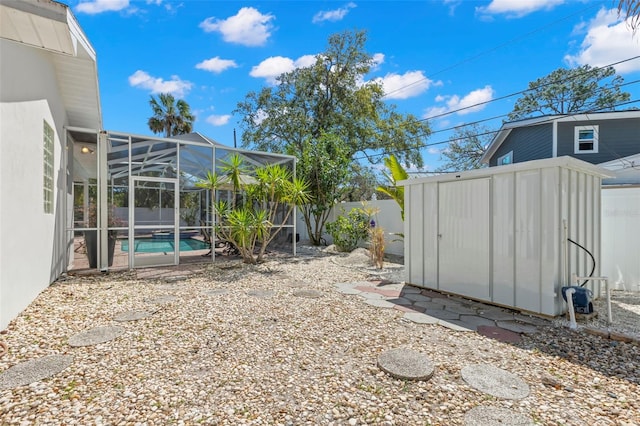 view of yard with glass enclosure, a fenced in pool, a fenced backyard, an outdoor structure, and a storage unit