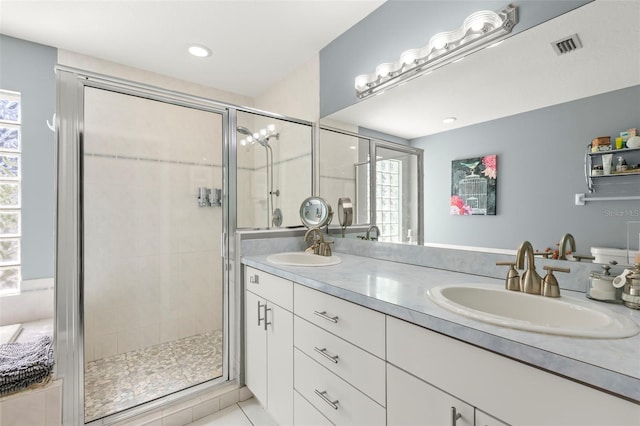 full bath featuring double vanity, visible vents, a stall shower, and a sink