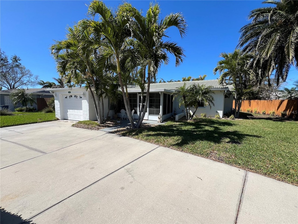 ranch-style house with fence, driveway, stucco siding, a front lawn, and a garage