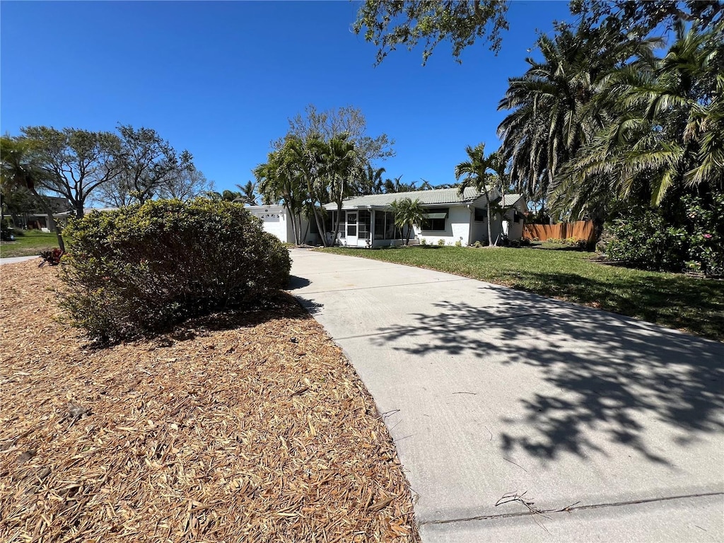 view of front facade featuring concrete driveway, fence, a front yard, and stucco siding