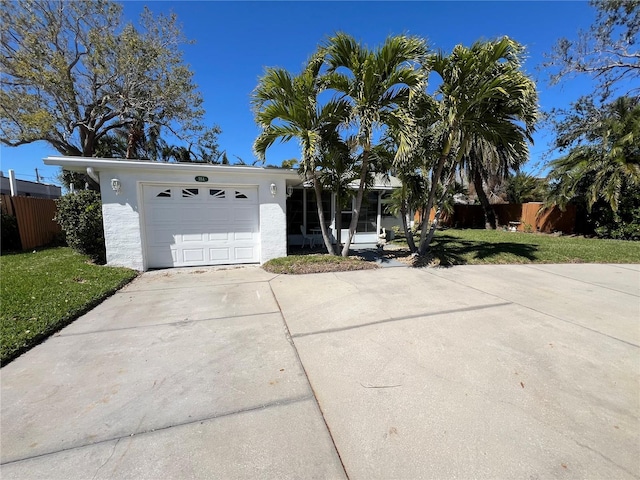 ranch-style home with stucco siding, a front lawn, driveway, fence, and a garage