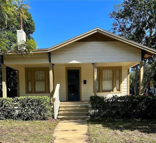 bungalow-style house featuring a porch and a chimney