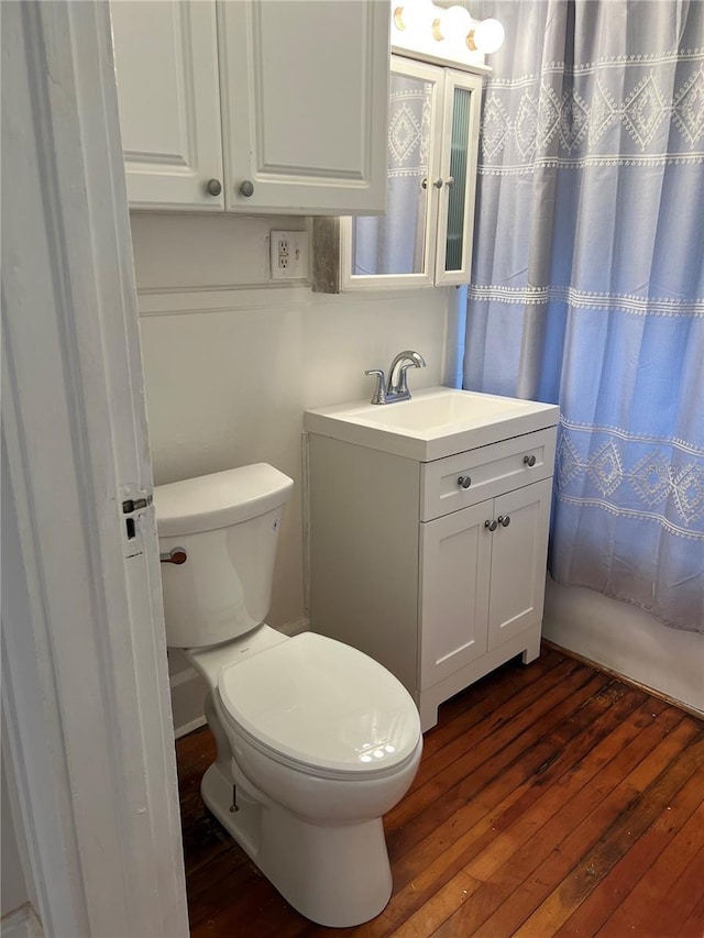 bathroom with a shower with curtain, wood-type flooring, toilet, and vanity