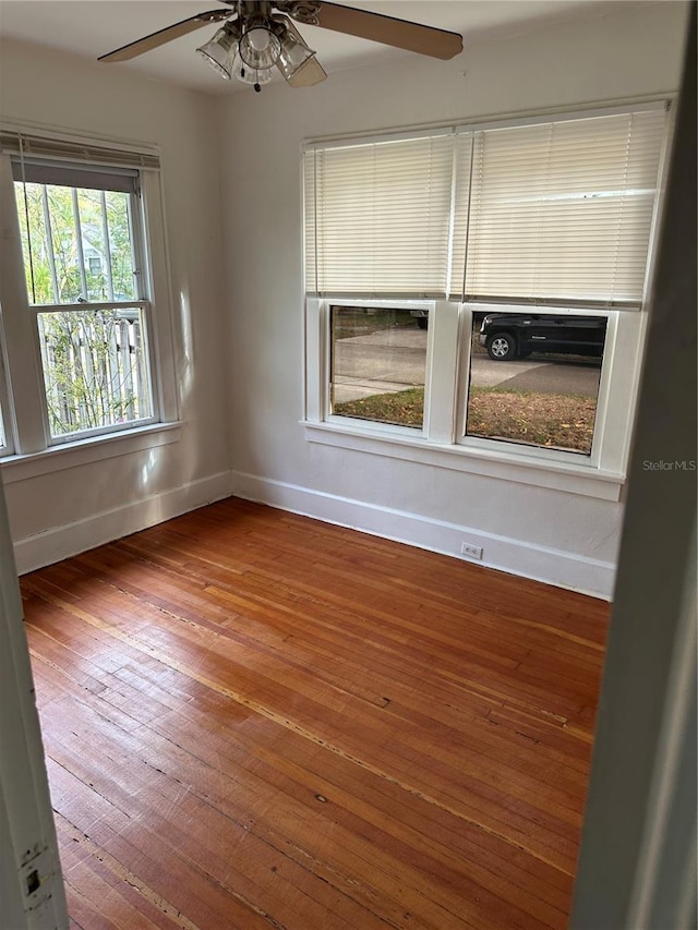 spare room featuring hardwood / wood-style floors, baseboards, and ceiling fan