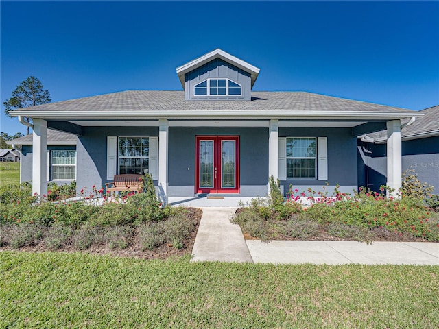 bungalow-style house with a front yard, french doors, covered porch, and stucco siding