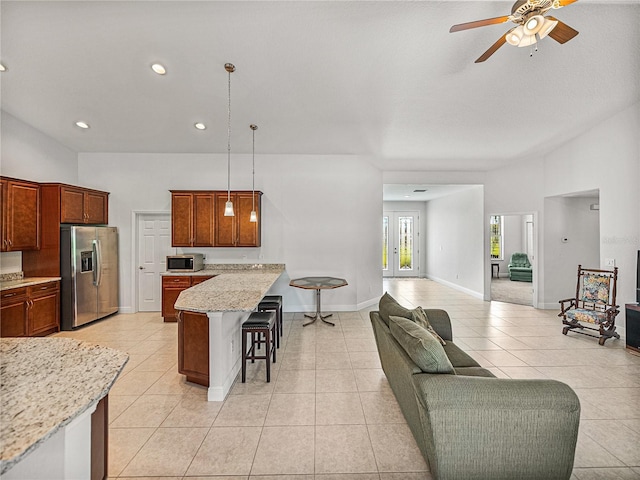 kitchen featuring a ceiling fan, open floor plan, a peninsula, a breakfast bar area, and appliances with stainless steel finishes