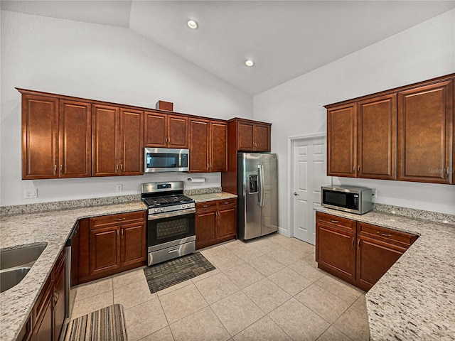 kitchen with light stone counters, recessed lighting, appliances with stainless steel finishes, light tile patterned flooring, and vaulted ceiling