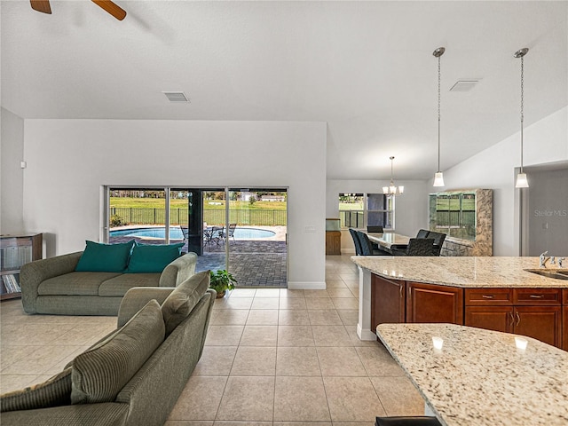 living area featuring visible vents, ceiling fan with notable chandelier, baseboards, light tile patterned flooring, and lofted ceiling