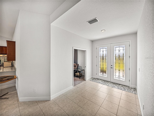 foyer entrance featuring light tile patterned floors, french doors, baseboards, and visible vents