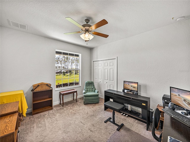 home office with carpet, a ceiling fan, visible vents, and a textured ceiling