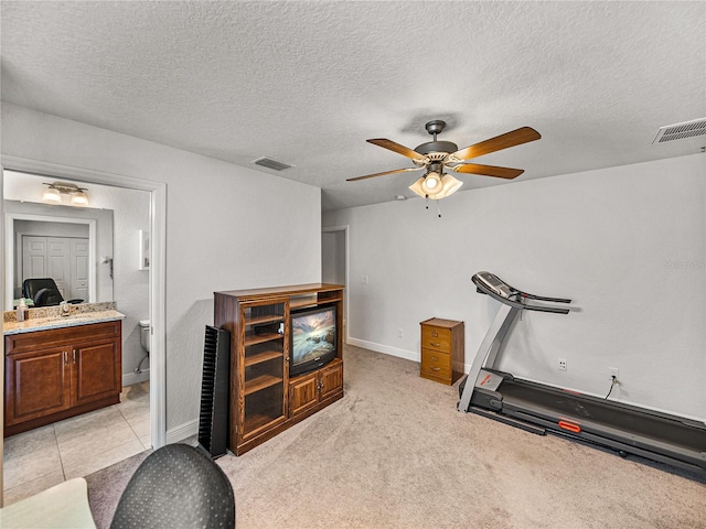 exercise room with visible vents, light colored carpet, a textured ceiling, and ceiling fan