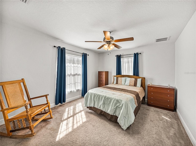 bedroom featuring multiple windows, baseboards, visible vents, and a textured ceiling