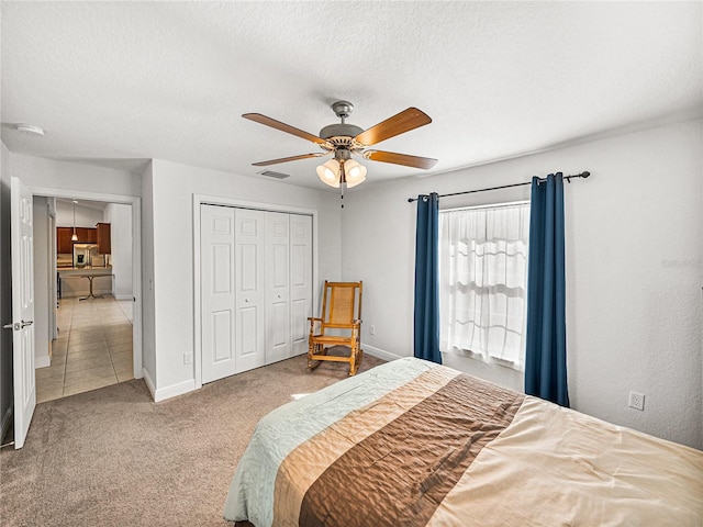 carpeted bedroom featuring visible vents, baseboards, ceiling fan, a closet, and a textured ceiling